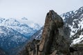 Large, craggy stone with low clouds and snowy mountain tops Royalty Free Stock Photo