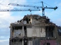 Large cranes over a large concrete building being demolished with exposed walls during redevelopment of a large urban site Royalty Free Stock Photo