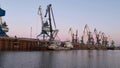 The large cranes at the sea port on sunset sky background. Clip. Big industrial machines and calm water surface, concept Royalty Free Stock Photo