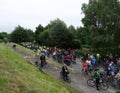 A large crowd of bicycle riders on a country road next to a