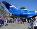 A large crowd of people women men children on holiday look at the tail of the aircraft walk