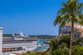 A large cruise ship stands in the port of Menorca next to yachts and palm trees, very close to the city streets, Spain Royalty Free Stock Photo
