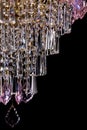 Large crystal chandelier with pink crystals details isolated on black background.