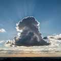 A large cumulus cloud dominates the center of the sky, backlit by the sun, creating a Royalty Free Stock Photo