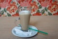 A large Cup of coffee with a saucer and a tube on the table. Wit