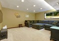 Large day-light open basement with green sofa, stove and TV.