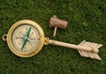 A large, decorative compass is placed on grass, designed to resemble a gold arrow. Royalty Free Stock Photo