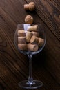 Large decorative glass tumbler, wine glass on a long stem, beautiful filled with wine corks lies on a wooden table. Corks are Royalty Free Stock Photo