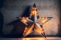 Large decorative retro star with lots of burning lights on grunge concrete background. Beautiful decor, modern design element. The Royalty Free Stock Photo
