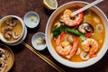 Large deep plate with tom yam soup with mushroom pieces and boiled shrimp