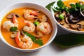 Large deep plate with tom yam soup with mushroom pieces and boiled shrimp