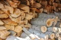A large, dense woodpile consisting of both split logs and unsplit branches. The split logs reveal light, textured inner wood, Royalty Free Stock Photo