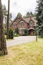 Large detached house exterior with brick walls and red roof behind a cobblestone path and green lawn in the summer Royalty Free Stock Photo