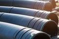 Large diameter black gasification pipes lie in a row in an open warehouse on the street on a summer day. Royalty Free Stock Photo