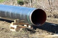 Large diameter pipe at local oil pipeline construction site supported with wooden supports on top of wet soil Royalty Free Stock Photo