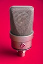 Large diaphragm condenser studio microphone Neumann tlm 103 on a red background.