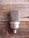 Large diaphragm condenser studio microphone Neumann tlm 103 on a wooden background.