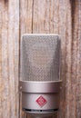 Large diaphragm condenser studio microphone Neumann tlm 103 on a wooden background.