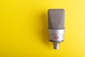 Large diaphragm condenser studio microphone Neumann tlm 103 on yellow background.