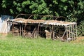 Large dilapidated wooden boxes filled with smaller boxes covered with large roof tiles and small greenhouse metal frame