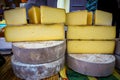 Large display of huge wheels of fresh cheese, at an outdoor farmers market in France