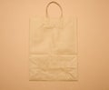 Large disposable brown kraft paper bag with handles on a brown background, eco packaging, zero waste