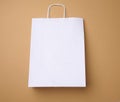 Large disposable white kraft paper bag with handles on a brown background, eco packaging