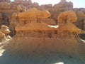 Large, double hoodoo rock formation in front of hills with various layers and textures