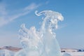 Large dragon head made of transparent ice against the blue sky