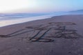 Large drawing on a sand beach picturing adult and a kid next to it