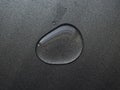 Large drop of water on gray metal surface - background