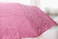 Large drops of rain flowing down pink umbrella closeup