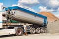 A large dump truck unloads rubble or gravel at a construction site. Car tonar for transportation of heavy bulk cargo. Providing