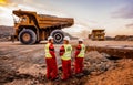 Large Dump Trucks transporting Platinum ore for processing with mining safety inspectors in the foreground