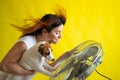 A large electric fan blows cold air onto a Caucasian woman and a dog. Girl with flying red hair under the influence of Royalty Free Stock Photo