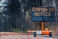 Large electronic notification sign on rural street announcing road closure due to Coronavirus Covid-19 pandemic