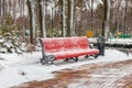 Large empty bench in a city park or garden on a winter day. Red bench and metal urn Royalty Free Stock Photo