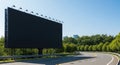 Large empty black billboard beside a winding road with trees and sky Royalty Free Stock Photo