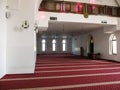 Large empty hall with red carpet, table and white walls of the Ar-Rahma Mosque in Kiev