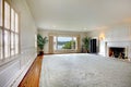 Large empty living room with fireplace and lake view.