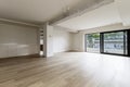 Large empty modern living room of a residential home with light wooden floors, exposed concrete beams and a terrace with sliding Royalty Free Stock Photo