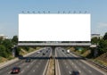 A large, empty white billboard is positioned above a multi-lane highway. Vehicles Royalty Free Stock Photo