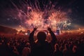 A large and enthusiastic crowd is captivated by a stunning fireworks show during a lively concert, Rear view of people in audience