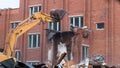 A large excavator breaks down the house, demolishing a building in the city Royalty Free Stock Photo