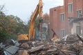 A large excavator breaks down the house, demolishing a building in the city Royalty Free Stock Photo