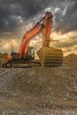 Large excavator on top of a mountain of sand and gravel