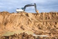 Large excavator working at construction site. Backhoe during earthworks on sand quarry. Earth-moving heavy equipment Royalty Free Stock Photo