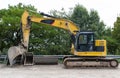 A large excavator in yellow color visible from the profile with a lowered bucket.