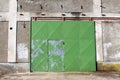 Large exterior green metal sliding warehouse doors with built in small entrance doors on rusted hinges Royalty Free Stock Photo