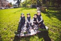 Large family Caucasian children. Three brothers and sister sitting resting on blanket outside the park. Green lawn grass Royalty Free Stock Photo